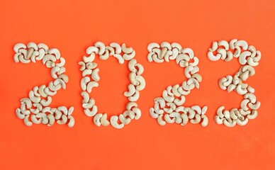 2023 Written with Cashew Nut Isolated on Orange or Red Background in Horizontal Orientation, Happy New Year 2023 Wishing Conceptual Photo
