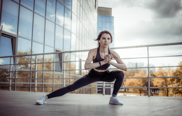 Young fitness woman doing warm up exercises near city building. healthy lifestyle