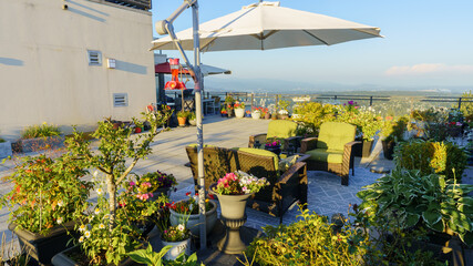 Umbrella with hummingbird feeder set amongst flowers and shrubs on BC rooftop patio garden with...