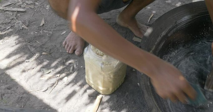 close up of a farmer puts paste of the palm sugar inside the small plastic container 