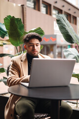 colombian stylish young man using laptop in cafe