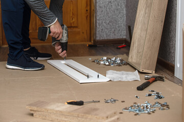 a male furniture craftsman assembles a cabinet case in a house. Repair and improvement of living...