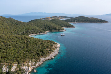 Fototapeta na wymiar Aerial view of sailboats and luxurious yachts at the coast of Mediterranean Sea. Pine tree forest and turquoise water of Bodrum, Turkey