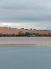 Sandy seashore. Calm water. The old ship on the shore. A plowed field. Minimalistic landscape.