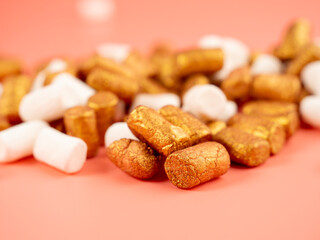 Mini marshmallows on a pink background. Marshmallow gold and white.