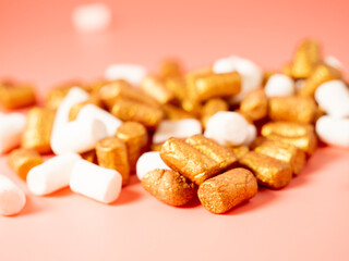 Fototapeta na wymiar Mini marshmallows on a pink background. Marshmallow gold and white.