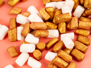 Mini marshmallows on a pink background. Marshmallow gold and white.