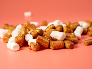 Mini marshmallows on a pink background. Marshmallow gold and white.