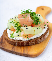 Healthy ham and cucumber open sandwich garnished with micro greens served on wooden board