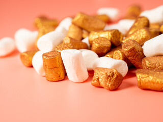 Mini marshmallows on a pink background. Marshmallow gold and white.