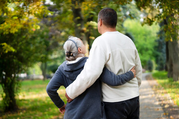 Naklejka na ściany i meble An elderly couple, man and woman walk in the autumn park.