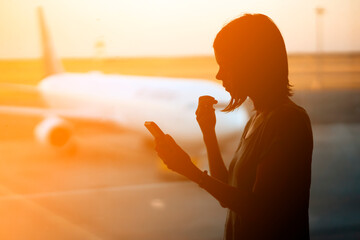 A silhouette of a girl in the rays of sun at the airport before the flight.