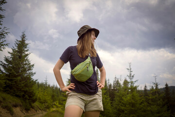 Girl is hiking in the mounntains and forest with waist bag.