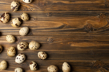 Fresh quail eggs on a brown wooden table. Raw quail eggs close up. Healthy food. The concept of preparation for cooking. Place for text. Place to copy.