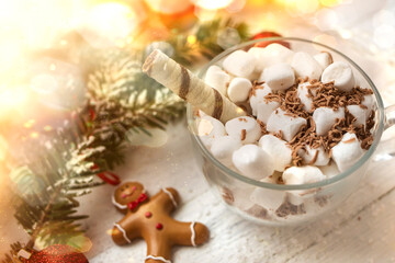 Christmas background. Cup of hot chocolate with marshmallows on a white wooden background with a gerland and a spruce branch.