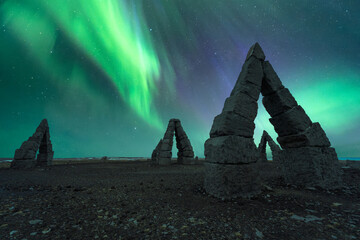 Silhouette of stony formations under northern lights
