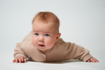 Fototapeta premium Portrait of an infant learning to crawl on a white background