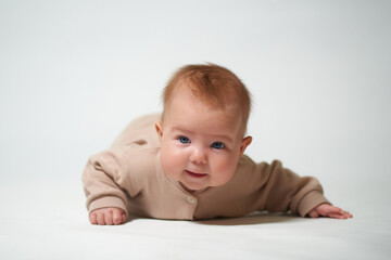 Fototapeta premium portrait of an infant looking into the camera who is learning to crawl on a white background