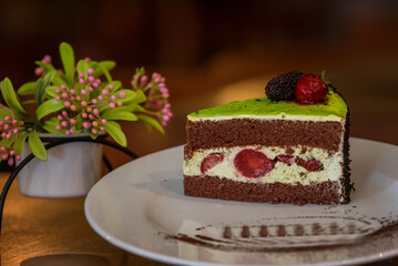 Piece of chocolate cake with icing and fresh berries on wooden background. Chocolate cake with strawberries on a wooden table close-up. Food. 