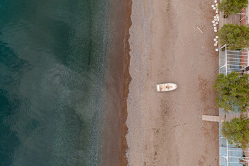 Aerial view of a small wooden boat on land beside turquoise water of Mediterranean Sea