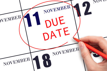 11th day of November. Hand writing text DUE DATE on calendar date November 11 and circling it. Payment due date. Business concept. Autumn month, day of the year concept.