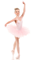 Young woman ballerina in white tutu, dancing on pointe with arms overhead, in the studio against a dark background.