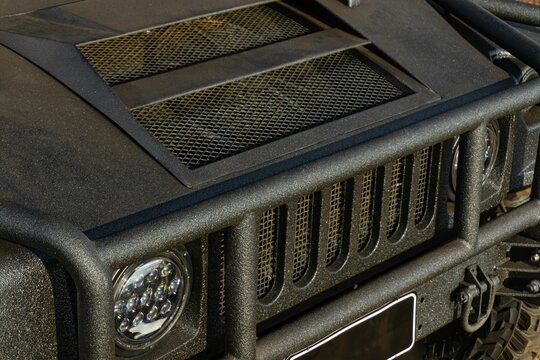 A closeup front view of an AM General Humvee in matte black - headlights, hummer grill