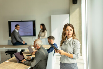 Young business woman at startup office with digital tablet in front of her colleagues as team leader