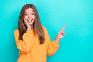 Photo of young funny cute teenager girl wear orange pullover touch cheeks finger point mockup black friday offer isolated on cyan color background