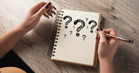 The girl drew question marks in a notebook