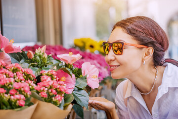 Naklejka premium A girl buyer and a client choose bouquets and flowers in pots at market and florist shop on a city street
