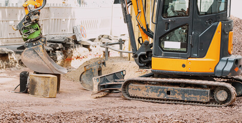Small excavator working on a construction site at city street. Equipment, labor and employment in...