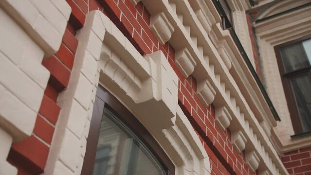 Elegant window with white brick frame on facade of vintage building closeup. Architectural heritage of urban site