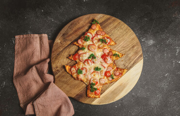 Pizza in the shape of a Christmas tree on a cutting board with a kitchen napkin lies on the left on...
