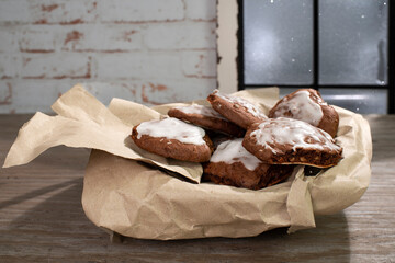 Homemade gingerbread biscuits with almonds and icing (Berlin bread) lie on wrapping paper. In the...