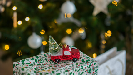 New Year's toy in the form of a car with a Christmas tree. Christmas toy on the background of Christmas lights.