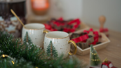 Two New Year's cups on the background of New Year's lights. Cups with New Year's print in the form of a Christmas tree. Decor for a New Year's feast