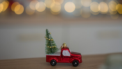 New Year's toy in the form of a car with a Christmas tree. Christmas toy on the background of Christmas lights.