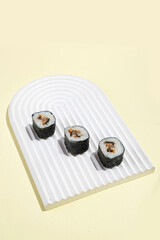 Asian culture, Japanese hosomaki (sushi, rolls) with eel on yellow background. Oriental culinary, eastern cooking.