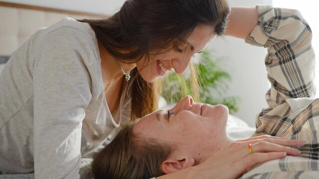 Couple of gay women in love lies on bed kissing sensually