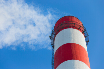 Pollution of the environment, ecology and air. Withdrawal of combustion products of soot, smoke and gases from the pipe of an industrial plant into the atmosphere against the background of a blue sky