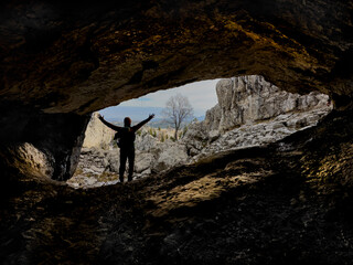 successful mountaineer and explorer watching the view from deep and wide caves in the mountains