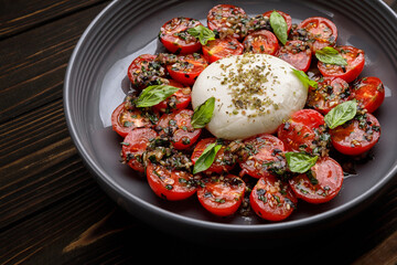 Baked tomatoes with mozzarella cheese, on a wooden background