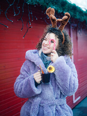 Smiling curly haired woman holding candy on festive christmas background