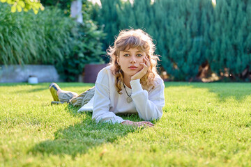 Portrait of cute teenage girl lying on grass looking at camera