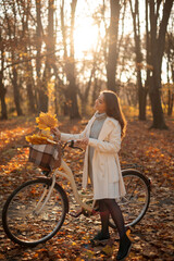 Vertical view of the happy active woman walking with bike in fall autumn park
