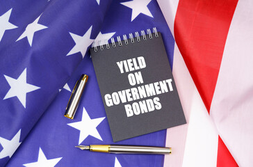 On the American flag lies a pen and a notebook with the inscription - Yield on government bonds