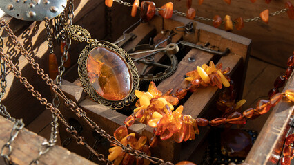 Transparent old Baltic pendant and different amber necklaces on an ancient wood. Different amber jewelry.