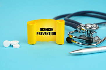 On a blue surface, a stethoscope, pills, a pen and a yellow sign with the inscription - DISEASE...