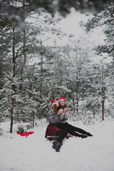 Close up fashion portrait of two sisters hugs and having fun, drinking tea winter time,wearing red santa hats and sweater,best friends couple outdoors, snowy weather
